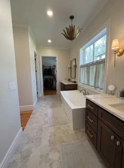 Long primary bathroom with a freestanding tub and tile floor