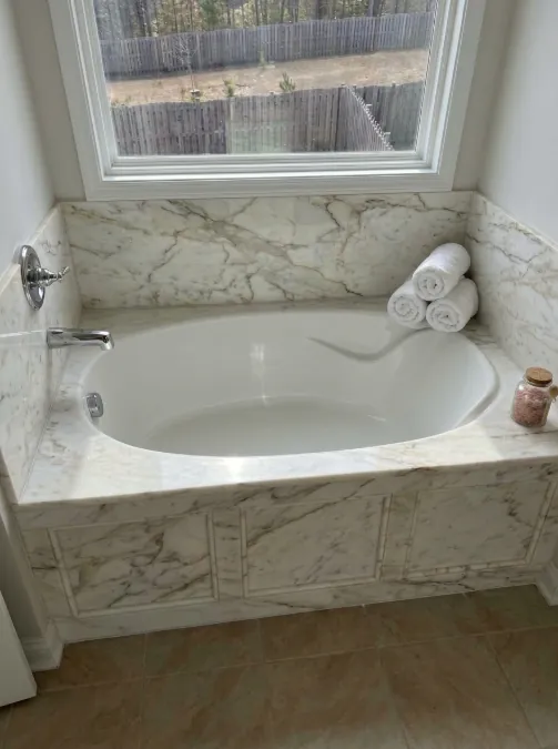 Soaking tub with a marble surround under a window