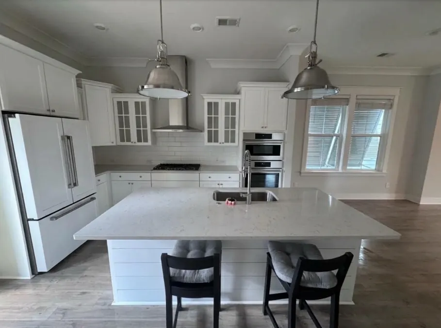 White kitchen with a large island and two black stools