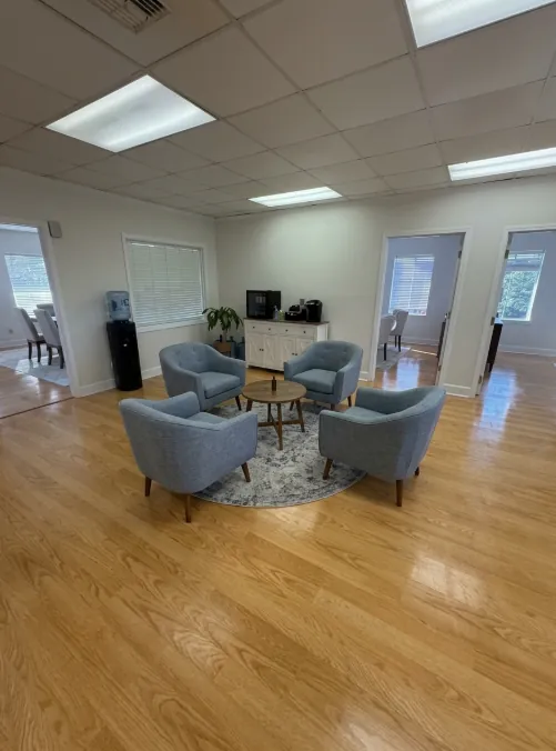 Office common area with four blue chairs and wood floors